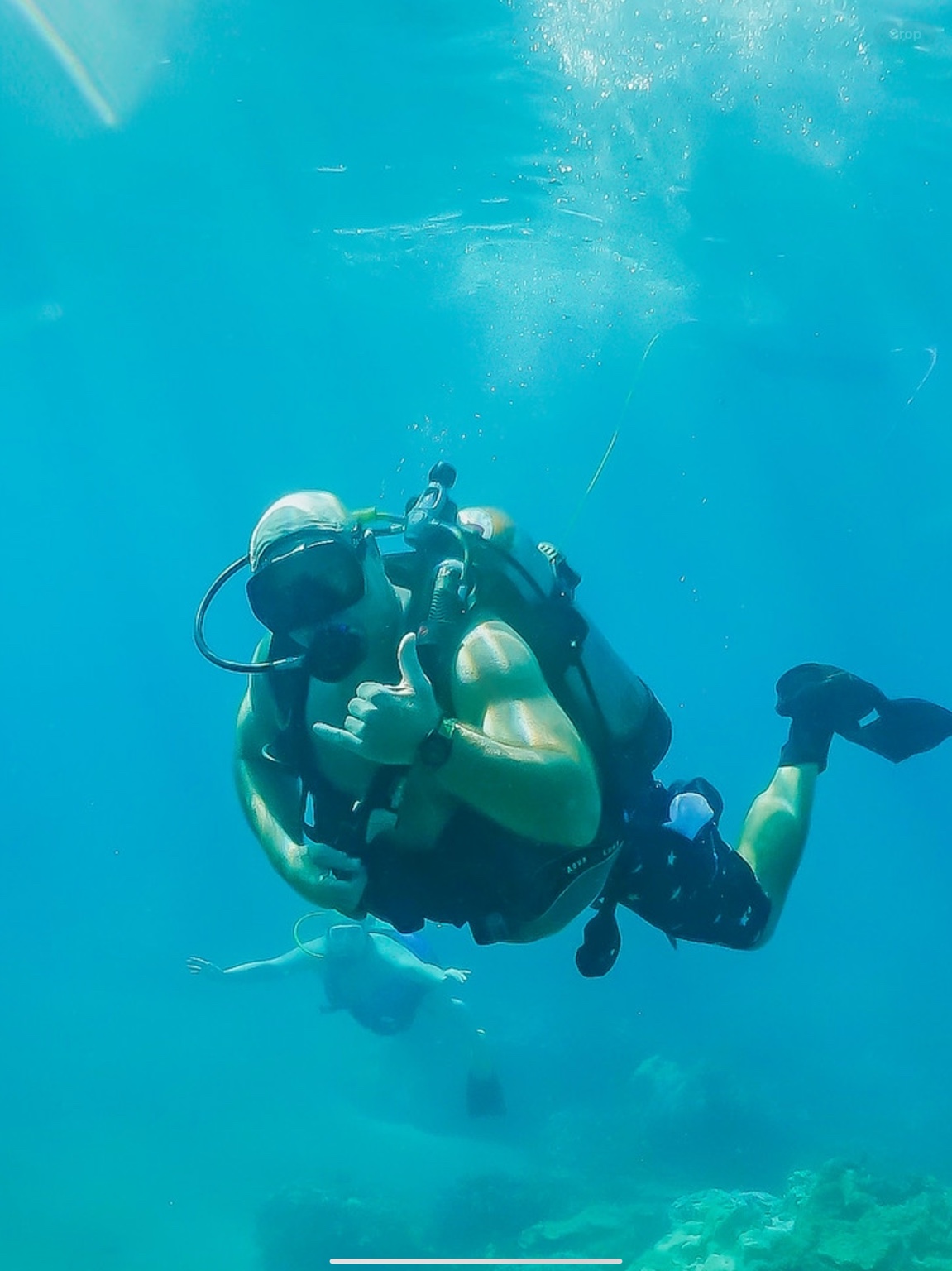 A guided tankless diver giving a shaka underwater in Maui